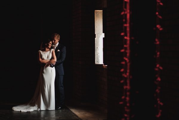 Bride & groom photographed in the light of an industrial looking window