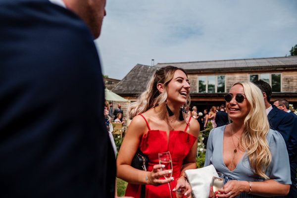 wedding guests laughing and drinking outside in the sun at Houchins Farm
