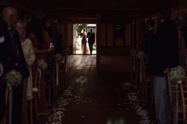 Street Photography Style Wedding Photographer capturing the entrance of the bride and her father as a silhouette